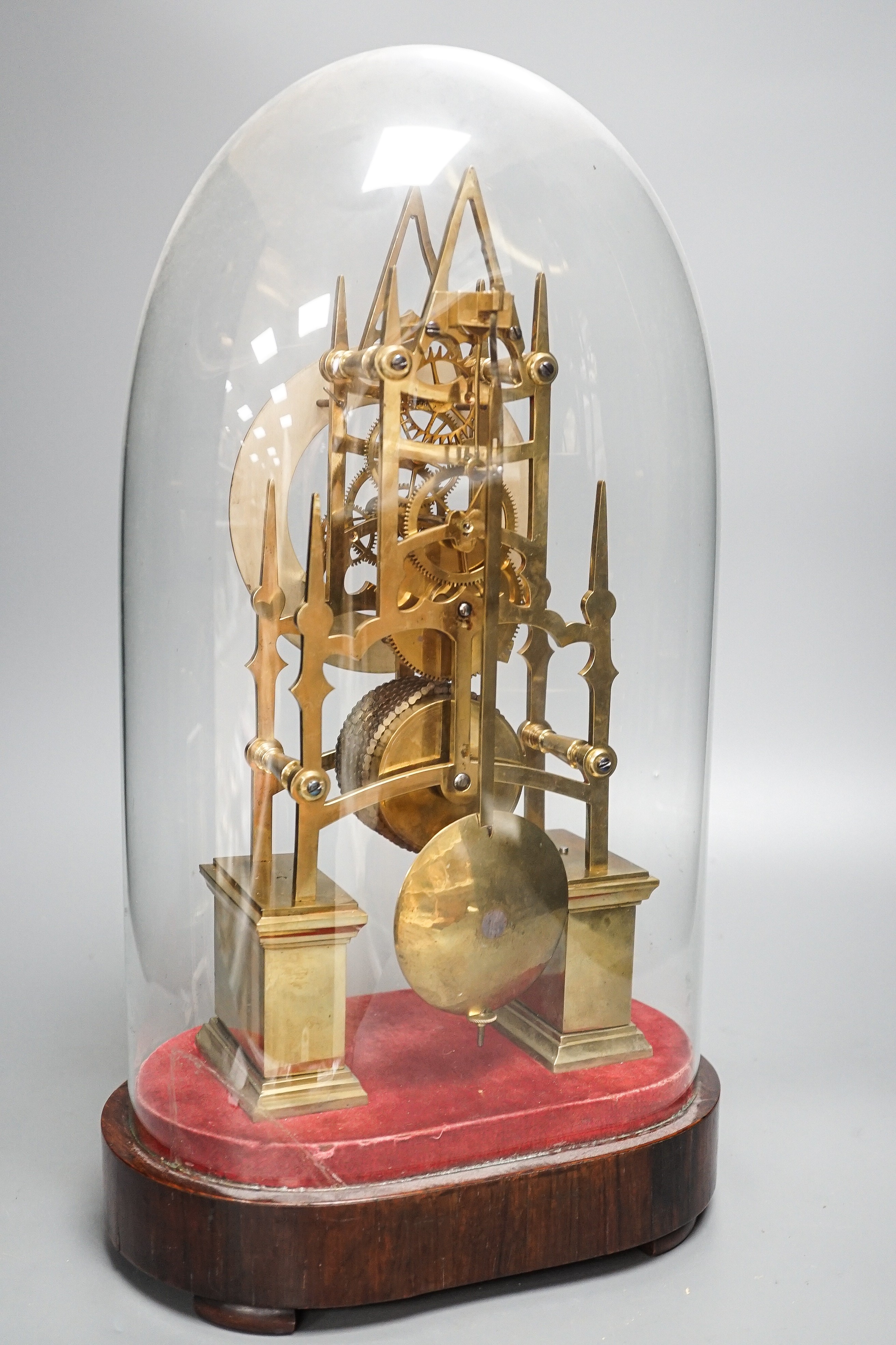 A Victorian brass skeleton clock, with single fusee movement, under a glass dome 43 cms high.
